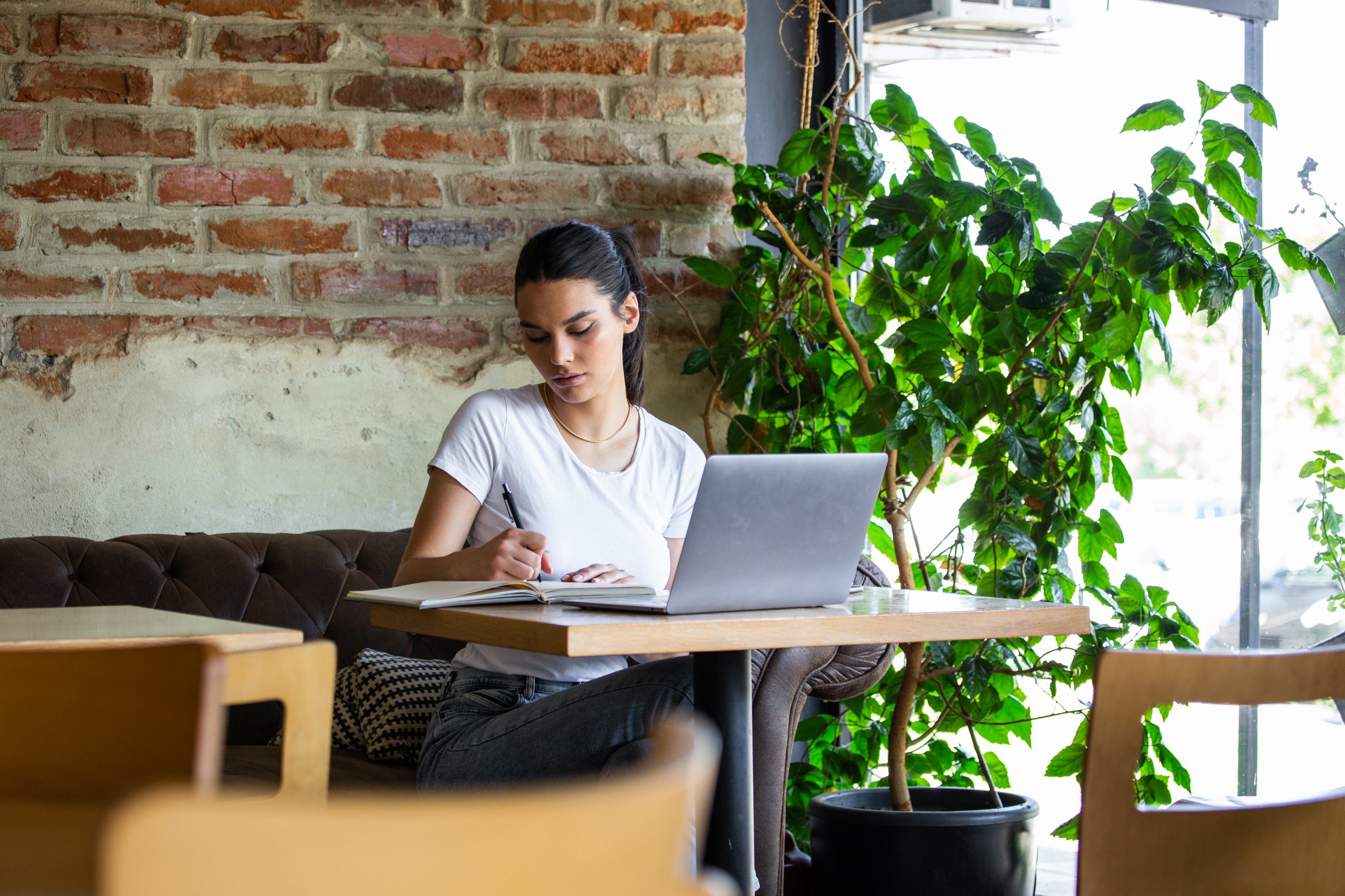 woman_in_white_tank_top_sitting_on_chair_using_macbook-scopio